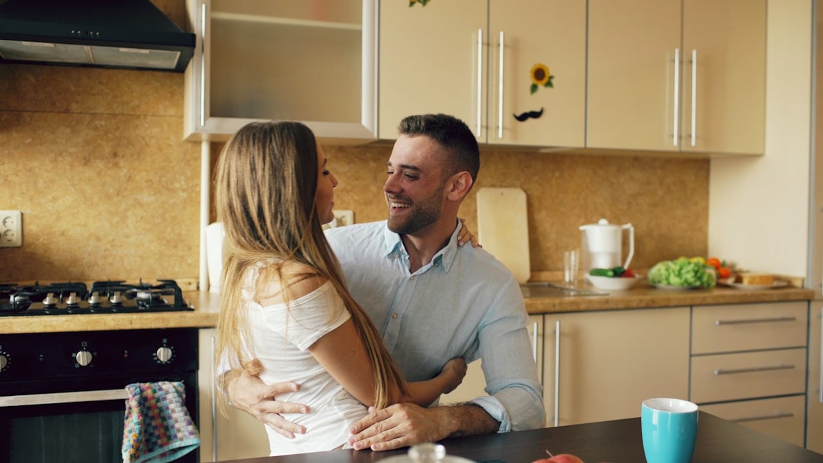 Attractive young couple embracing early morning in the kitchen.